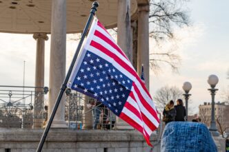 An upside-down US flag displayed in the foreground of a gathering at a bandstand in Boston Common.