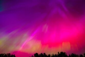 Vibrant aurora borealis lighting up the night sky with strong pink, magenta, and purple hues.