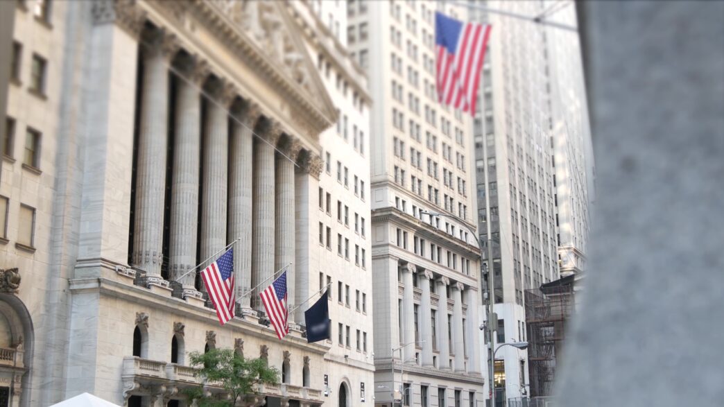 New York Stock Exchange building facade with US flags in Lower Manhattan's Financial District.