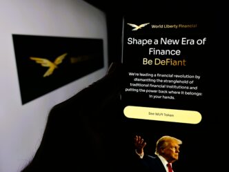 Phone screen displaying the World Liberty Financial crypto webpage with Trump's image and slogan.