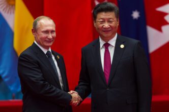 Chinese President Xi Jinping and Russian President Vladimir Putin shake hands and smile at the G20 summit.