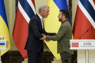 Zelenskiy and Store shake hands after a press conference, flanked by Ukrainian and Norwegian flags.