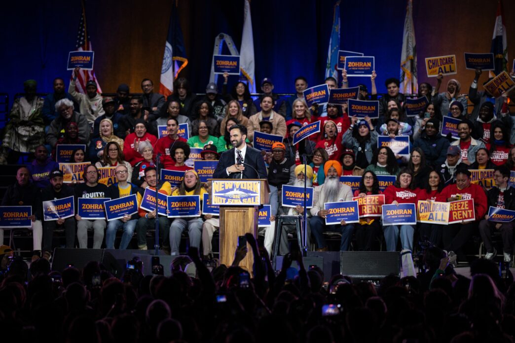 Close-up, high-angle portrait of New York City Mayoral candidate Zohran Mamdani smiling slightly.