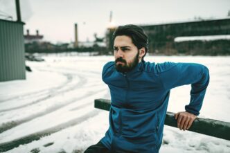 A young man stretches and exercises outdoors near an old railroad in the winter.