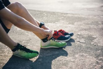 A person wearing running shoes sprints across a stadium track.