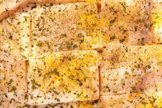 Top-down view of a background made of square pieces of cod fillet, seasoned with spices.