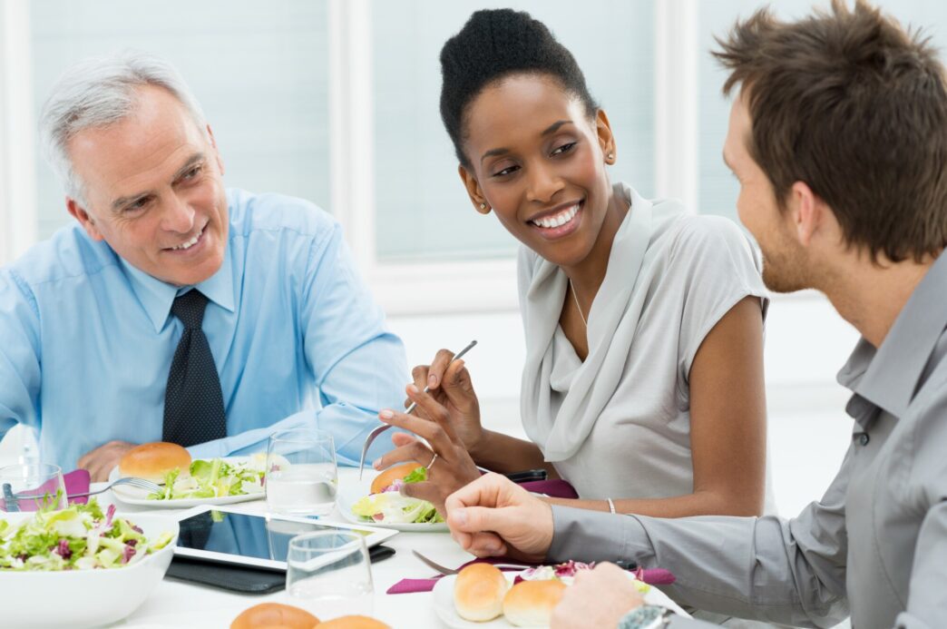 A group of diverse business professionals enjoys a meal together at a restaurant.