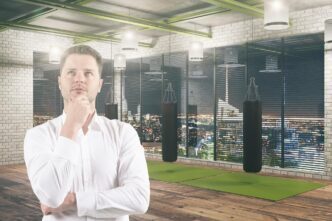 A businessman in a suit stands in a gym.