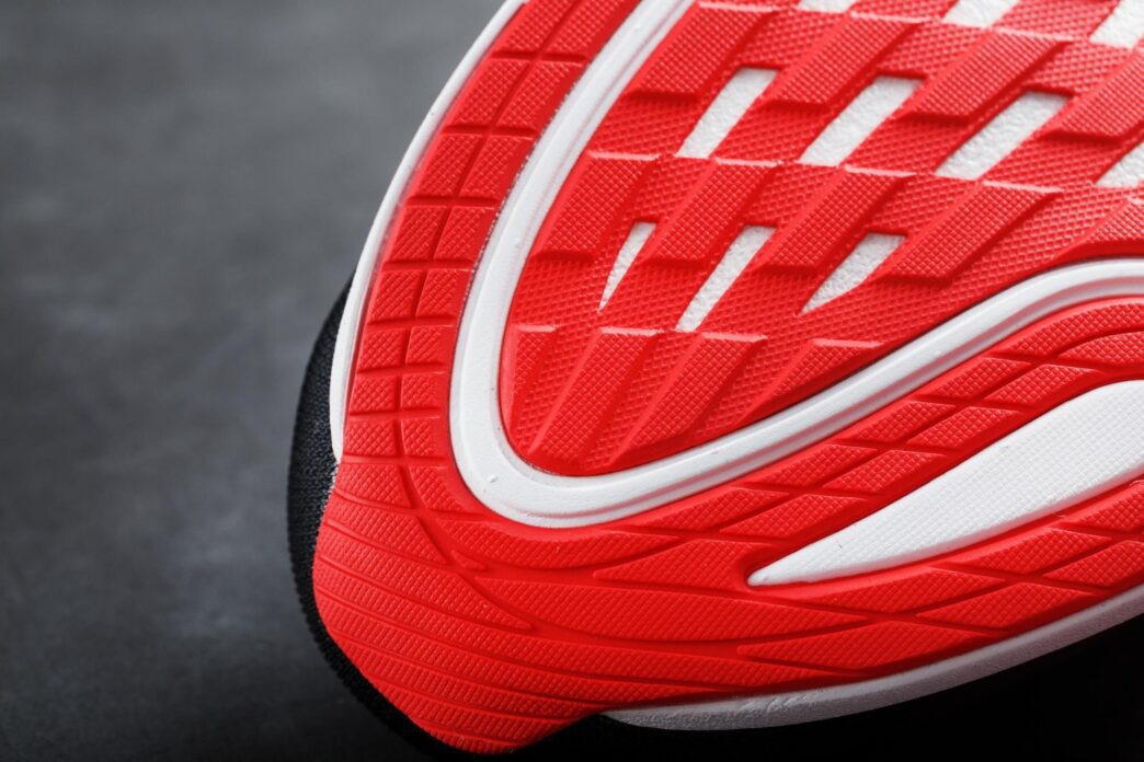 Close-up of the red sole of a running shoe, showing the tread pattern.