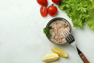 Canned tuna is presented on a white, textured surface, representing the concept of a tasty meal.