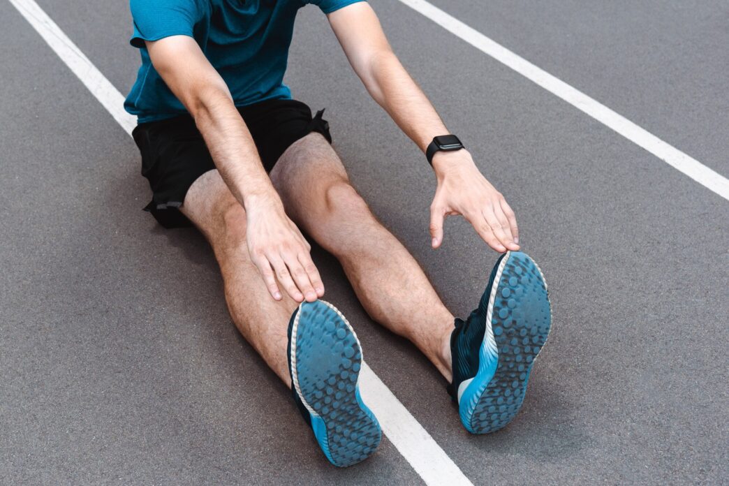 A young sportsman stretches on a running track.
