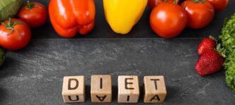 Top-down view of healthy food items arranged around diet text on a dark wooden surface.