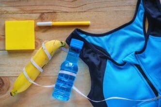 Close-up of a sports bra, water bottle, and banana arranged on a table.