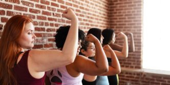 Group of diverse women flex their muscles, celebrating strength and empowerment.