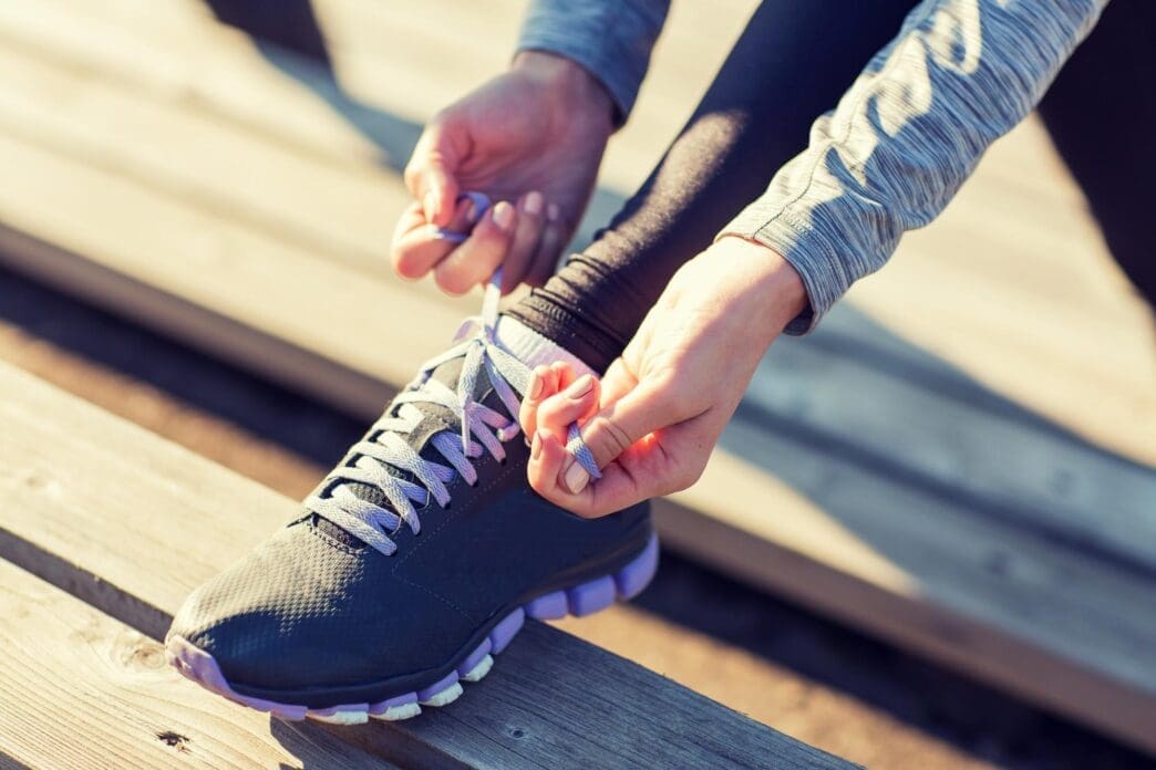 Close-up of a young woman tying her shoelaces outdoors, preparing for a workout.