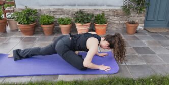 A person in a kneeling pushup pose, demonstrating a yoga practice.