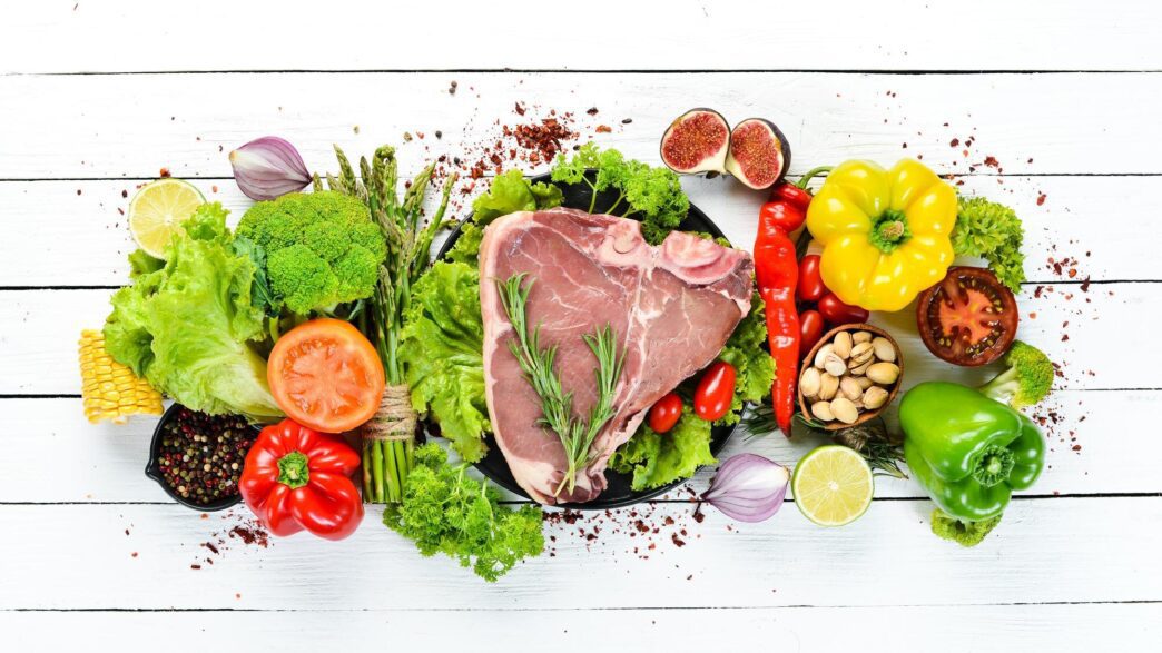 Overhead shot of raw meat surrounded by cooking ingredients with space for text.