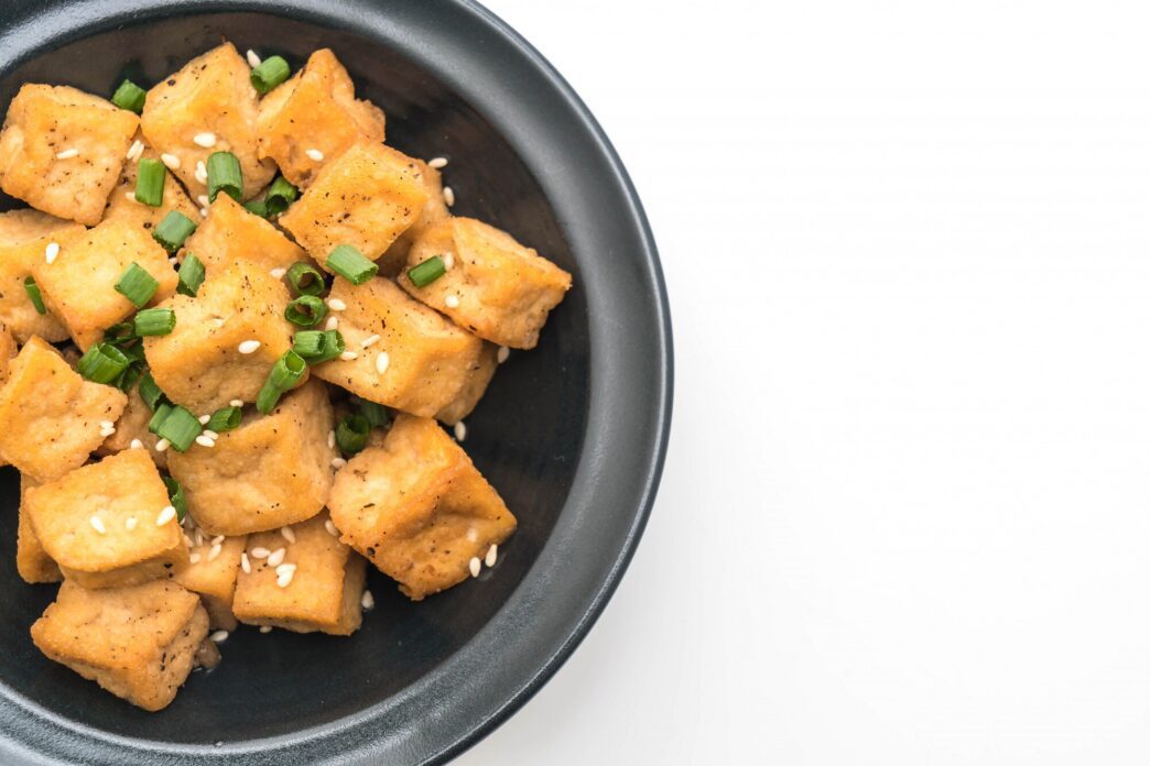 Bowl of crispy, golden-brown fried tofu sprinkled with sesame seeds.