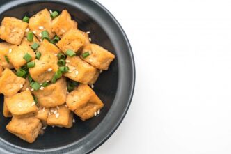 Bowl of crispy, golden-brown fried tofu sprinkled with sesame seeds.