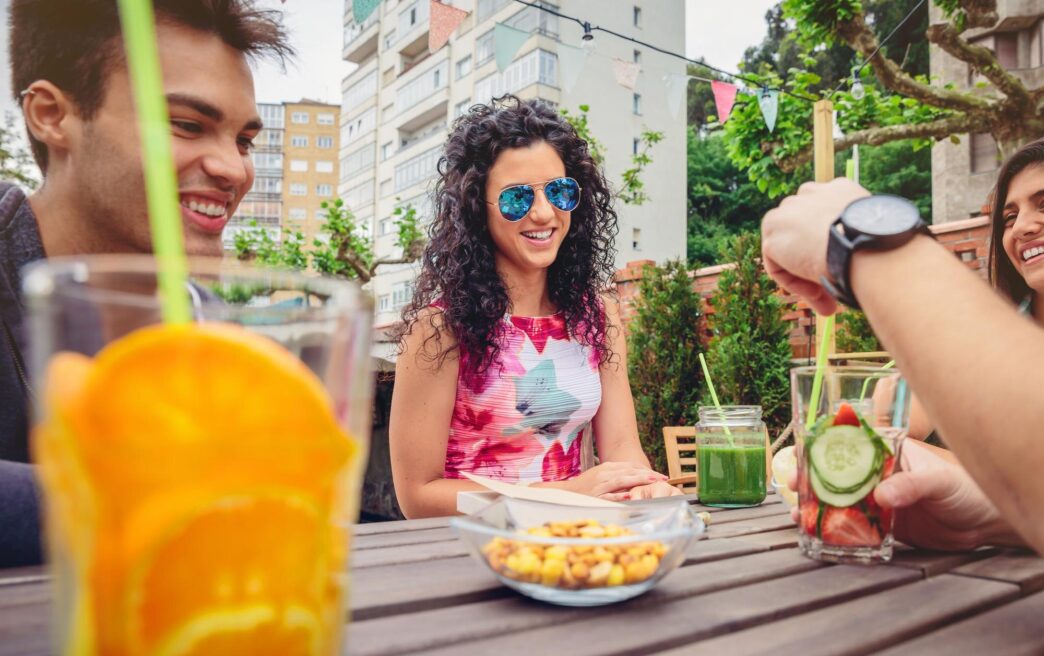 Friends smiling and clinking glasses while enjoying drinks at a restaurant table.