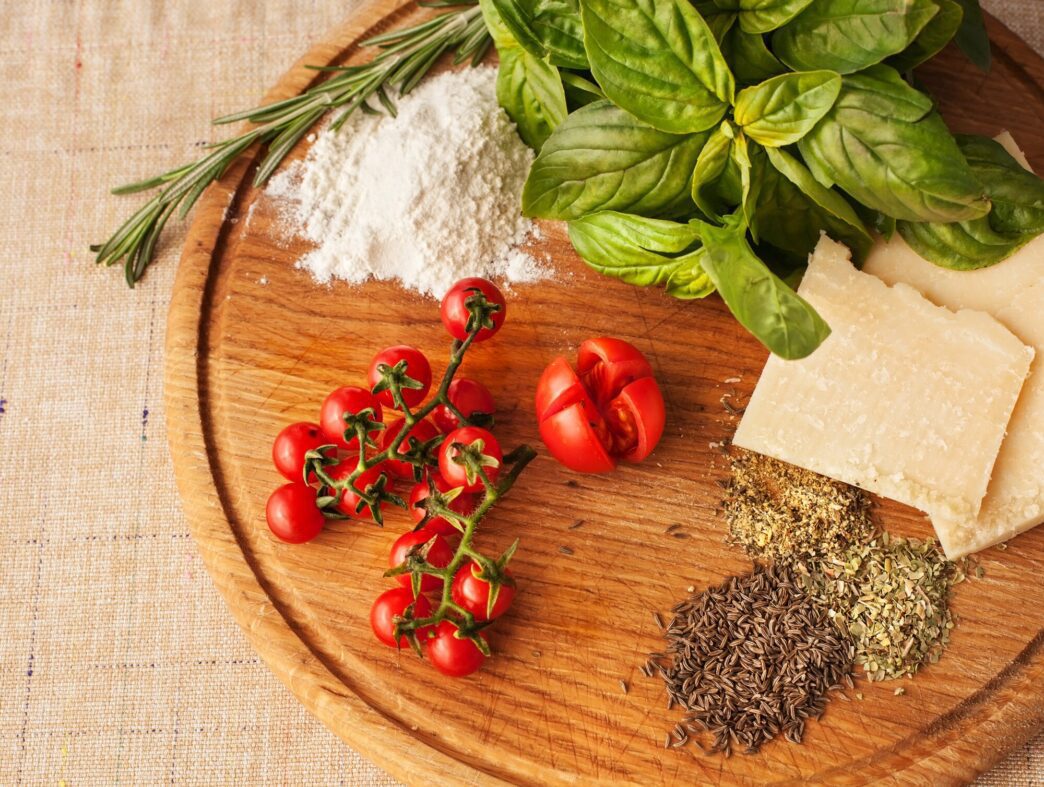 Close-up of fresh ingredients commonly used in Italian cuisine, including tomatoes, basil, garlic, and olive oil.