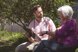 A male doctor reviews medical reports with an elderly woman.