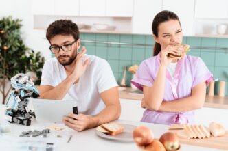 A man examines a small robot while reading a tablet.
