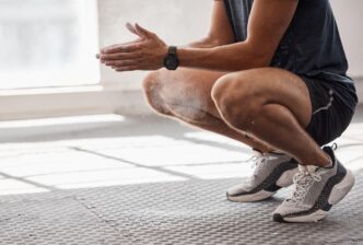 A man powders his hands with chalk while preparing to lift weights in a gym.