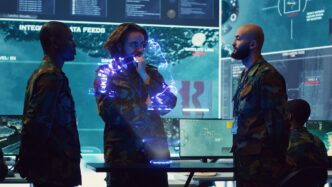 Soldiers in military uniforms examine an augmented reality display showing simulated enemy equipment.