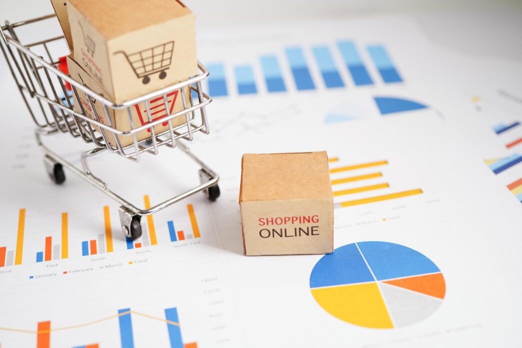 A shopping cart icon sits atop a bar graph, representing online shopping within the context of business, finance, and commerce.