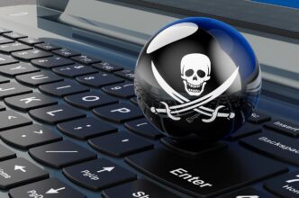 A 3D rendering depicts a black pirate flag with a skull and crossbones resting on the keys of a laptop keyboard.