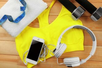 Assorted sports clothing and equipment, such as shoes and balls, are arranged on a wooden surface.