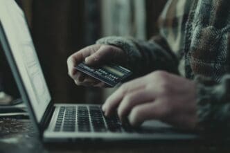 A detailed, high-resolution image shows a man using a laptop to pay with a credit card, emphasizing vibrant colors.