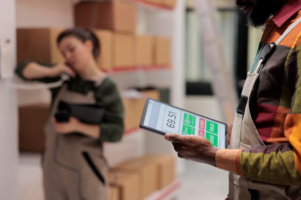 Warehouse supervisor in a high-visibility vest holding a tablet computer.