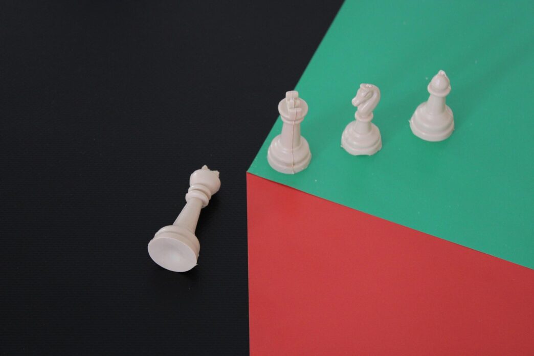A white chess piece sits beside a green and red square.