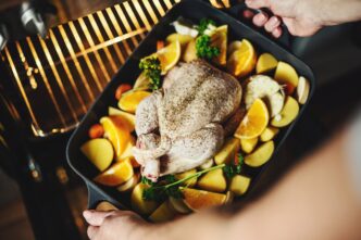 A woman prepares raw chicken and vegetables in a kitchen setting.