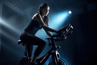 A woman in a dark-colored outfit rides an exercise bike, depicted in a style with black and light blue tones.