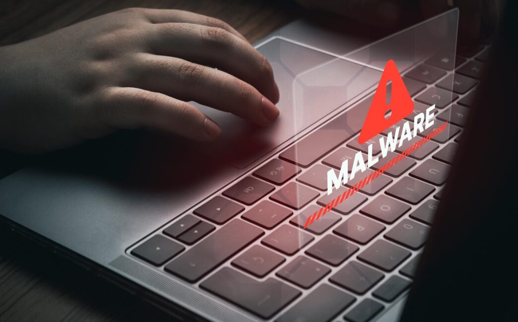 A woman uses a laptop, highlighting a screen displaying a malware alert, representing compromised information.