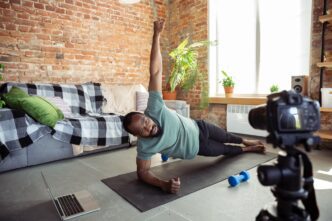 A young Black man leads an online fitness class from his home.
