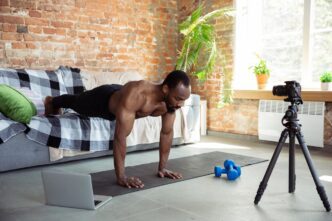 A young Black man leads an online fitness class from his home.