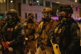Police in tactical gear standing ready during a SWAT standoff.