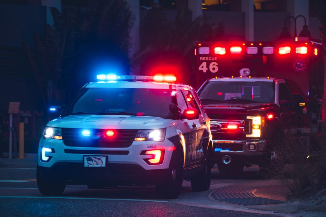 American police car and emergency truck with flashing blue and red lights at night.