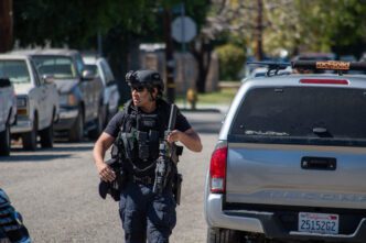 An armed SWAT officer moves tactically down a suburban street.