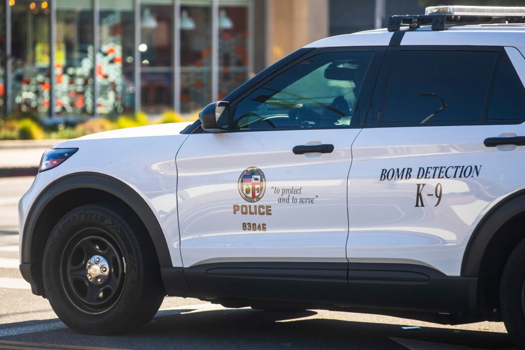 White Ford SUV Bomb Detection K-9 unit with emergency lights on during the day, photographed by Karolis Kavolelis.