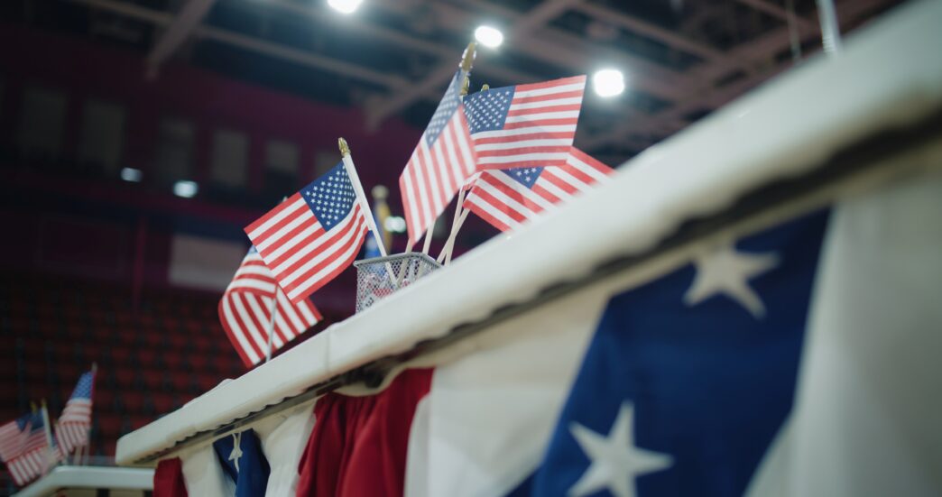Close-up of a voting registration table with American flags at a polling place.
