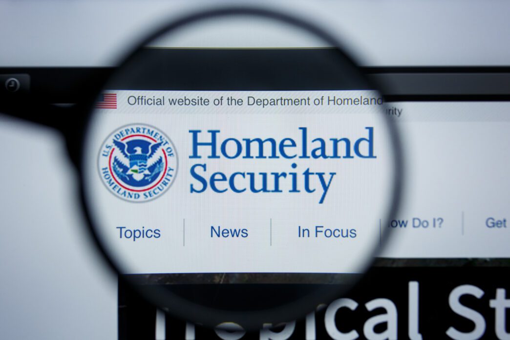 Magnifying glass focuses on the DHS logo and text on its website homepage.