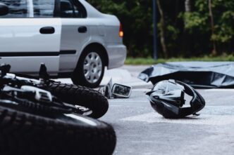Motorcycle helmet on the street after a fatal accident with a car, showing debris and damaged vehicles.