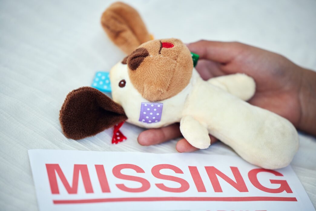 A hand holds a stuffed toy near a paper with "MISSING" printed, highlighting concern for missing children.