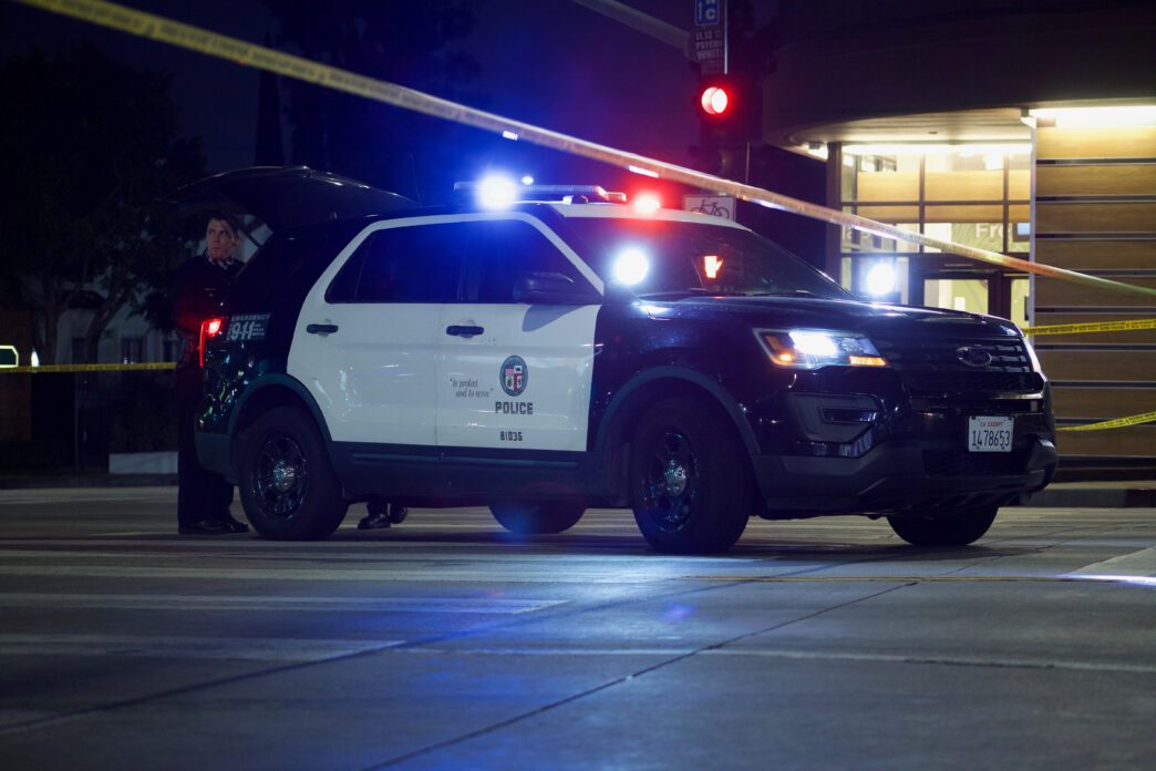 Police car and yellow tape block street at night after shooting; credit Elliott Cowand Jr-Shutterstock.