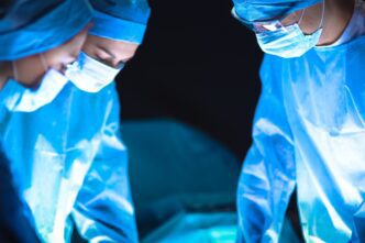 Surgeons in blue scrubs performing surgery in an operating room, captured by lenetstan for Shutterstock.